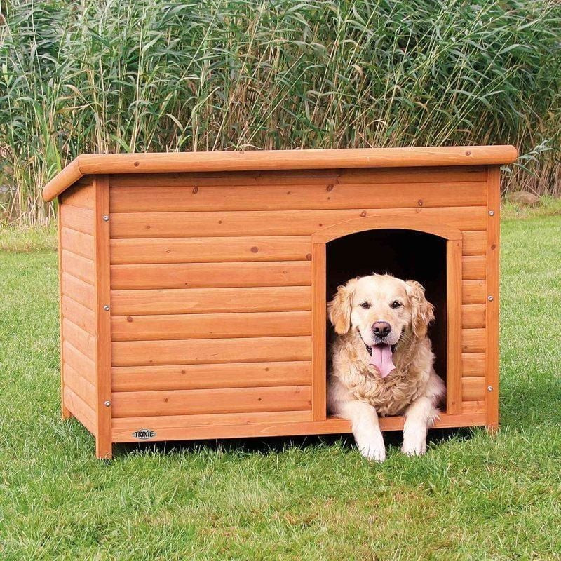 Niche chien Trixie Natura Classic placée dans un jardin avec herbe et fleurs.