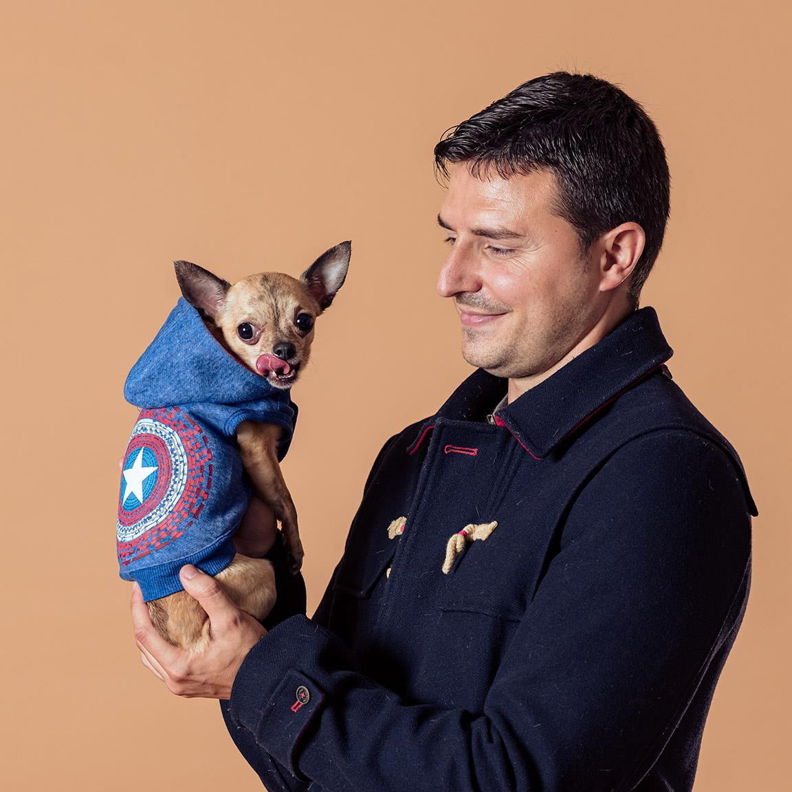 A dog standing outside wearing a Captain America-inspired sweatshirt with stars and stripes pattern.
