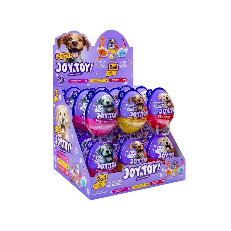 Dog playing with VADIGRAN Joy & Toy surprise egg, holding it in mouth. Ambient scene showing dog enj