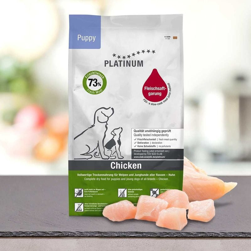 Sac Platinum Puppy Poulet 5kg sur table avec morceaux de poulet frais cru à côté, mettant en avant l