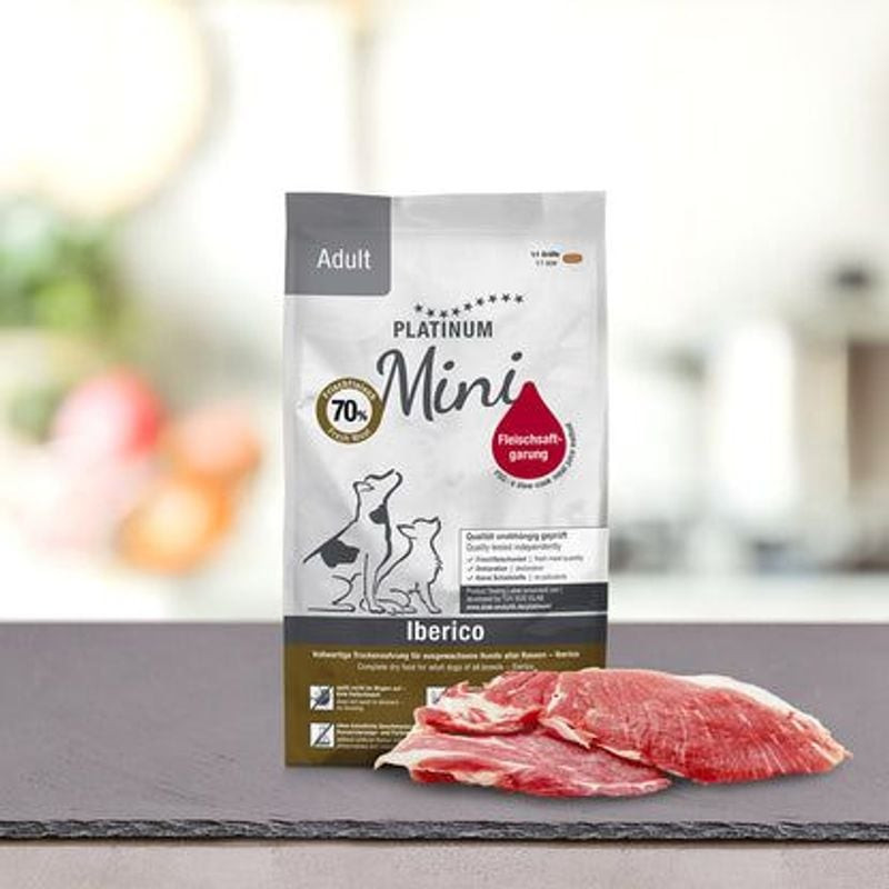 Scène avec sachet PLATINUM Adult Mini Ibérique & Greens et bol de croquettes, soulignant les ingrédi