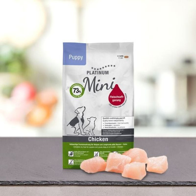 Paquet Platinum Puppy Chicken Mini 900g en ambiance naturelle sur table, montrant croquettes roses s