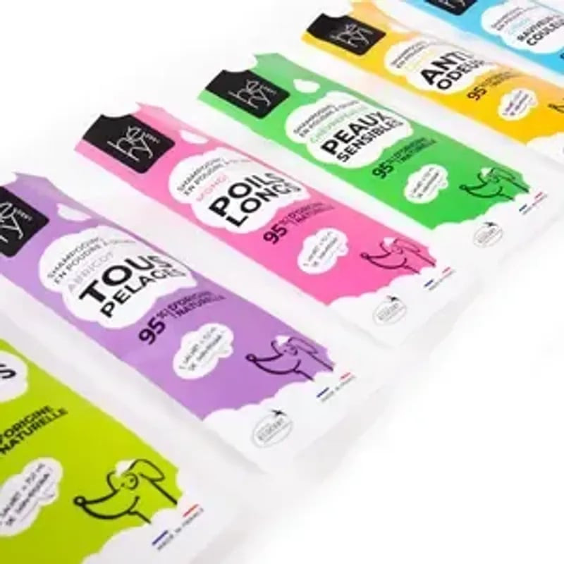 Alignement organisé de sachets de shampoing poudre Héry en diverses couleurs et formules : chiot cot