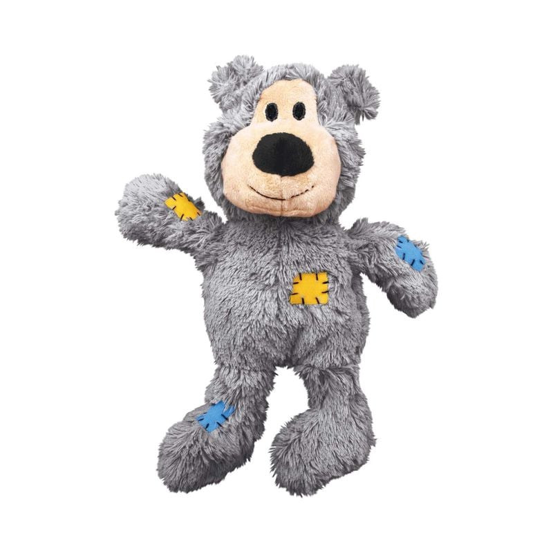 Jouet pour chien KONG Wild Knots Bear XS gris en peluche avec patchs tissu jaune et bleu, posé dynam