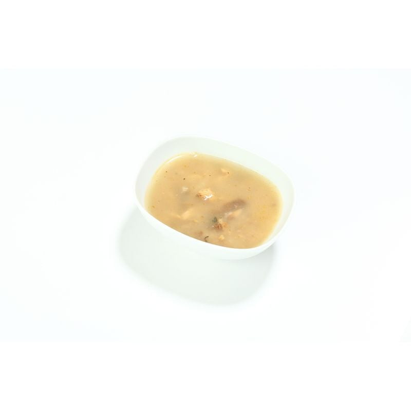 Gros plan de la soupe à la sardine Almo Nature dans un bol blanc, montrant un bouillon doré épais av
