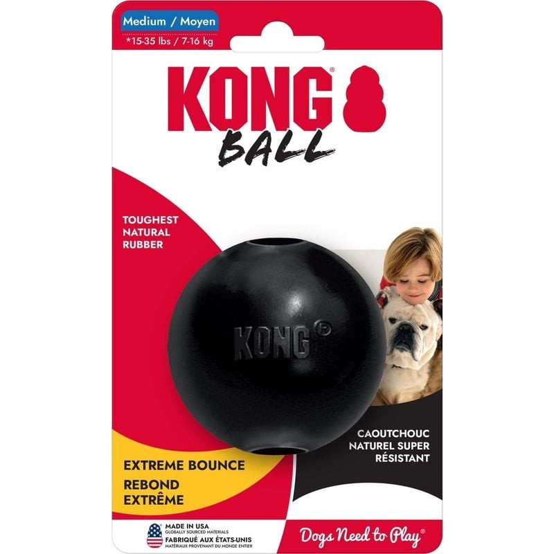 Chien noir mâchant la balle KONG Extreme en extérieur, emballage indiquant taille M pour chiens 7-16