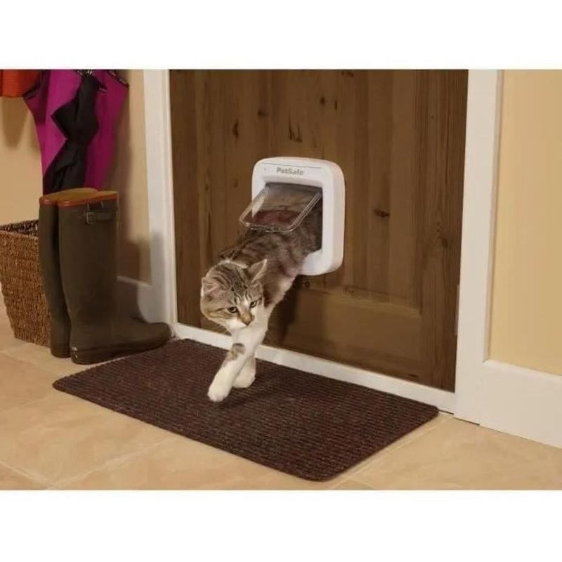Chatière électronique PetSafe installée sur une porte en bois, chat entrant par celle-ci.